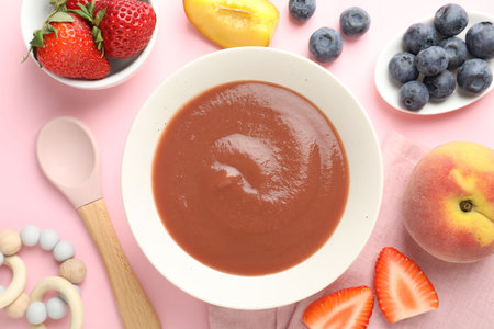 Baby food. Tasty puree in bowl, teether and ingredients on pink background, flat layの写真素材