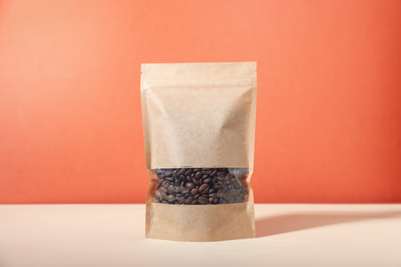 One zipper stand-up pouch with coffee beans on white table against red background. Mockup for designの写真素材