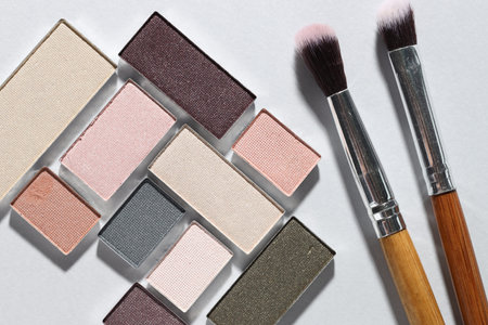 Beautiful eyeshadow refill pans and brushes on light background, flat lay