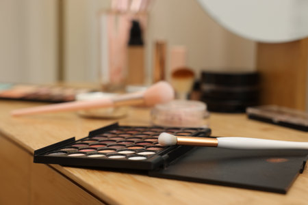 Eyeshadow palette and brush on wooden table, closeup