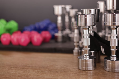 Many dumbbells on floor in fitness studio, closeup. Space for text