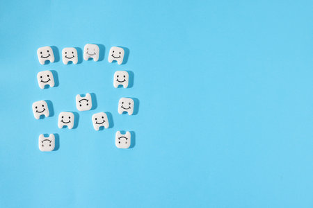 Tooth made with small teeth figures on light blue background, flat lay. Space for text