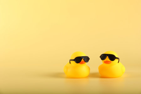 Cute rubber ducks on yellow background, space for text