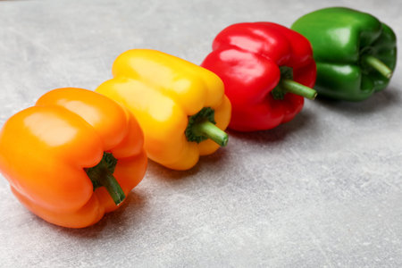 Fresh colorful bell peppers on gray textured table, closeup