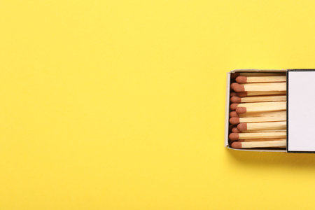 Matches in box on yellow background, top view. Space for text