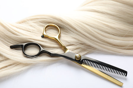 Hair lock and scissors on white background, above view