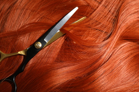 Scissors on red hair lock, top viewの写真素材