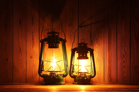 Two vintage kerosene lanterns on wooden table