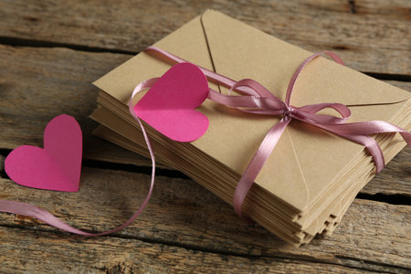 Stack of love letters and paper hearts on wooden table, closeupの写真素材