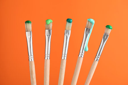 Many brushes with color paints on orange background, closeupの写真素材
