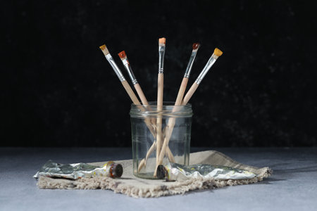 Brushes in jar and color paints on grey tableの写真素材