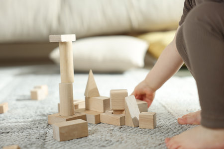 Cute little child playing with wooden building blocks at home, closeupの写真素材