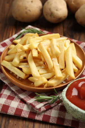 Tasty french fries served with ketchup and rosemary on wooden table, closeupの写真素材