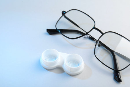 Case with contact lenses and glasses on white background, closeup