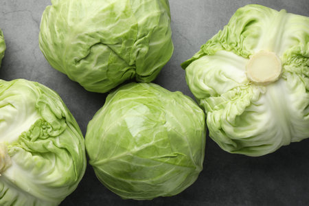 Fresh green cabbages on grey table, flat lay