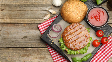 Delicious hamburger patty, bun, vegetables and spices on wooden table, flat lay. Space for textの写真素材