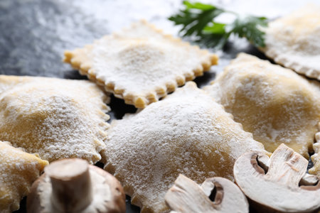 Uncooked ravioli, parsley and mushrooms on black table, closeupの写真素材