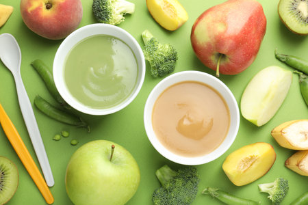 Baby food. Tasty puree in bowls and ingredients on green background, flat layの写真素材
