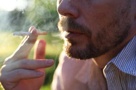 Man smoking cigarette on blurred background, closeupの写真素材