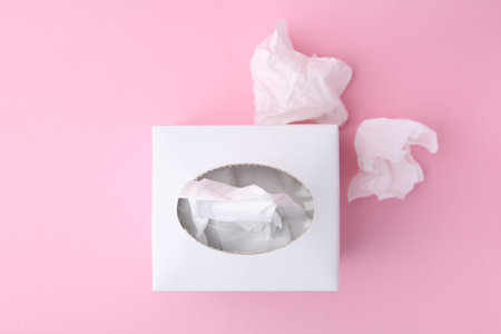 Box with paper handkerchiefs and crumpled tissues on pink background, flat layの写真素材