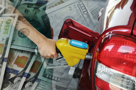 Fuel price. Gas station attendant refueling car, double exposure with dollar banknotesの写真素材