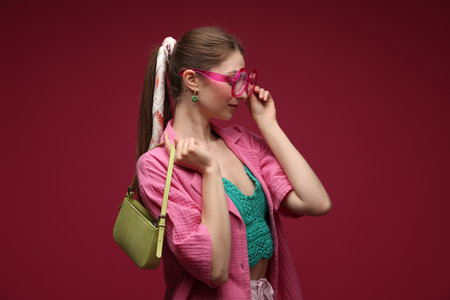 Fashionable portrait of beautiful woman in stylish outfit on dark red backgroundの写真素材