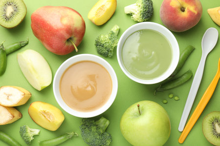 Baby food. Tasty puree in bowls and ingredients on green background, flat layの写真素材