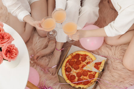 Pajama day. Friends with glasses of alcoholic drink and pizza on faux fur, above viewの写真素材