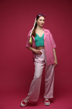 Fashionable full-length portrait of beautiful woman in stylish outfit on dark red backgroundの写真素材