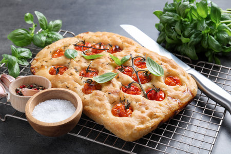 Delicious focaccia with tomatoes, spices and knife on table, closeupの写真素材