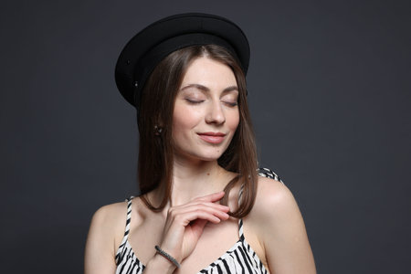 Fashionable portrait of beautiful woman in stylish outfit on grey background