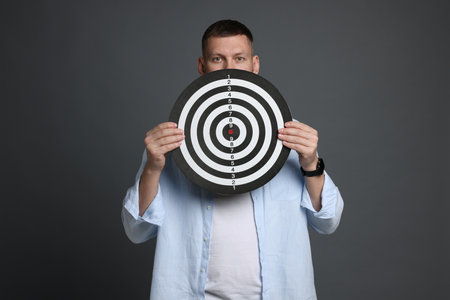 Targeting. Man with dart board on grey backgroundの写真素材
