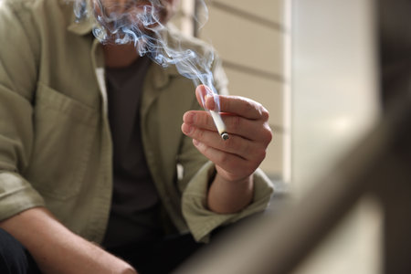 Man smoking cigarette on blurred background, closeupの写真素材