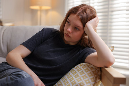 Sad teenage girl on sofa at homeの写真素材