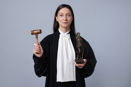 Judge with mallet and figure of Lady Justice on gray backgroundの写真素材