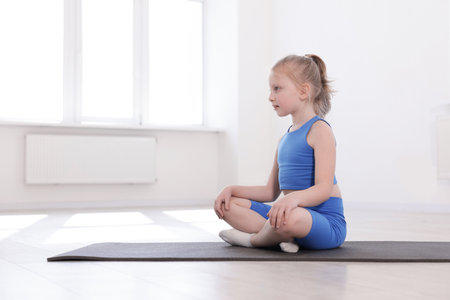 Cute girl sitting on yoga mat indoorsの写真素材