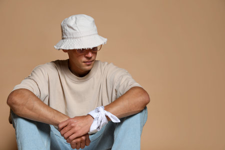 Fashionable portrait of handsome man in stylish outfit on brown background, space for text