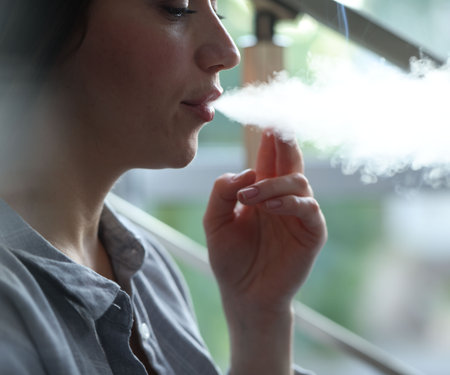 Woman smoking cigarette indoors, closeup.