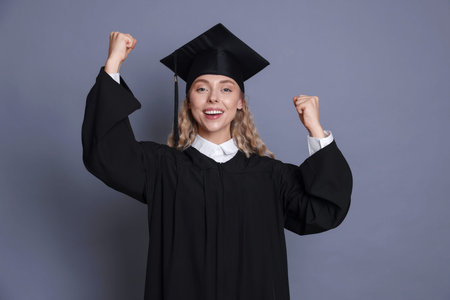 Happy student after graduation on grey background