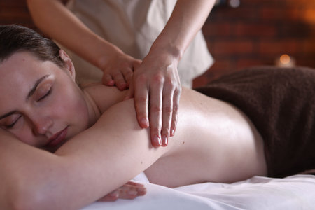 Woman receiving back massage with oil in spa salonの写真素材