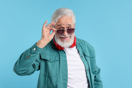 Elderly man in stylish outfit on light blue backgroundの写真素材