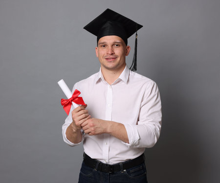 Happy student with diploma after graduation on grey backgroundの写真素材