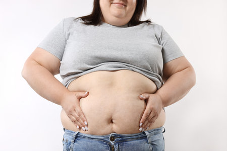 Woman with excessive belly fat on white background, closeupの写真素材