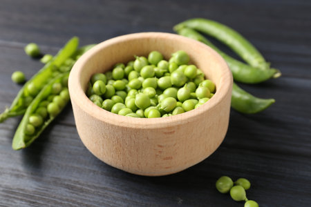 Fresh ripe green peas on black wooden table, closeupの写真素材