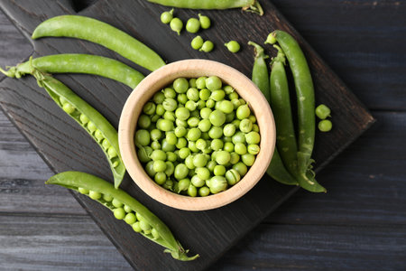 Fresh ripe green peas on black wooden table, flat layの写真素材