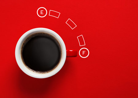 Coffee and fuel gauge scale on red background, top view. Handle of cup pointing at Full mark. Energizing property of caffeineの写真素材