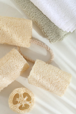 Different loofah sponges and towels on white table, flat layの写真素材