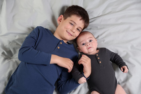 Cute little brothers on bed, top view
