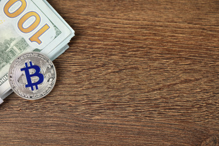Cryptocurrency. Bitcoins and dollar banknotes on wooden table, top view. Space for textの写真素材