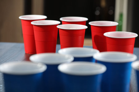 Beer pong game. Plastic cups with drinks on table, closeup